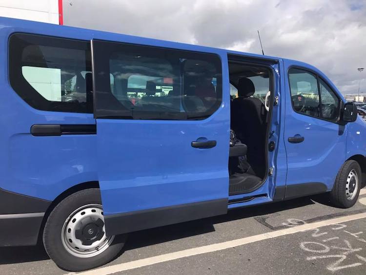 Large blue passenger rental van that you can reserve with AutoSlash and save money