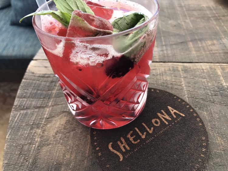 pretty pink happy hour cocktail on a coaster on a wooden table