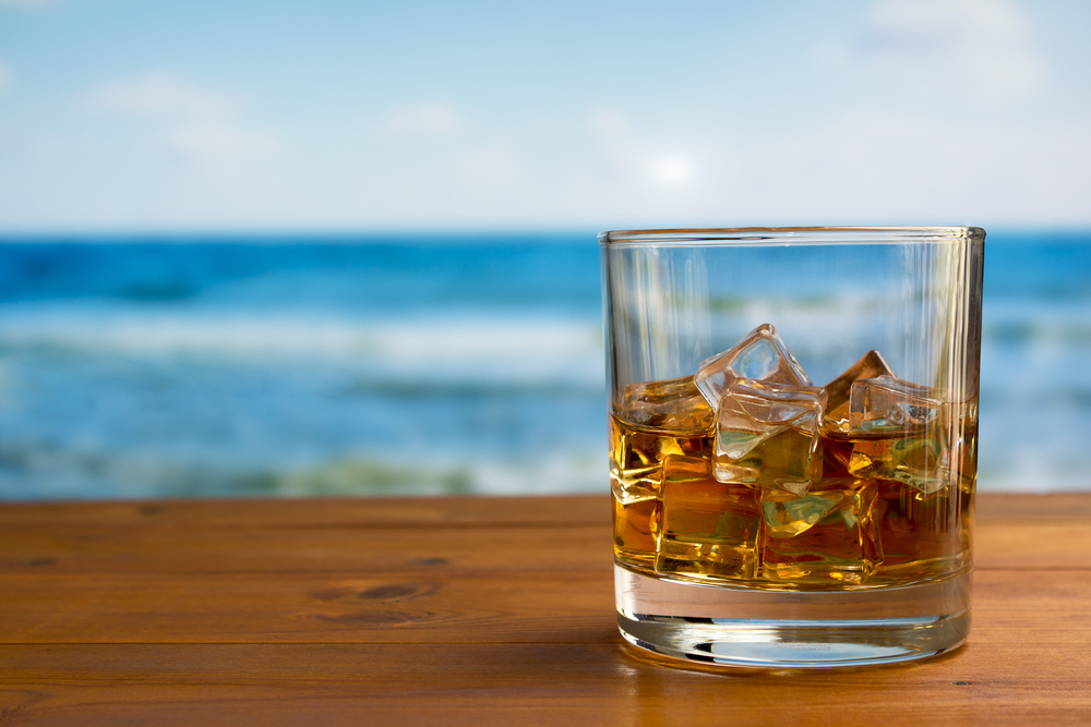 whiskey on the rocks with beach in background, a simple whiskey cocktail for summer