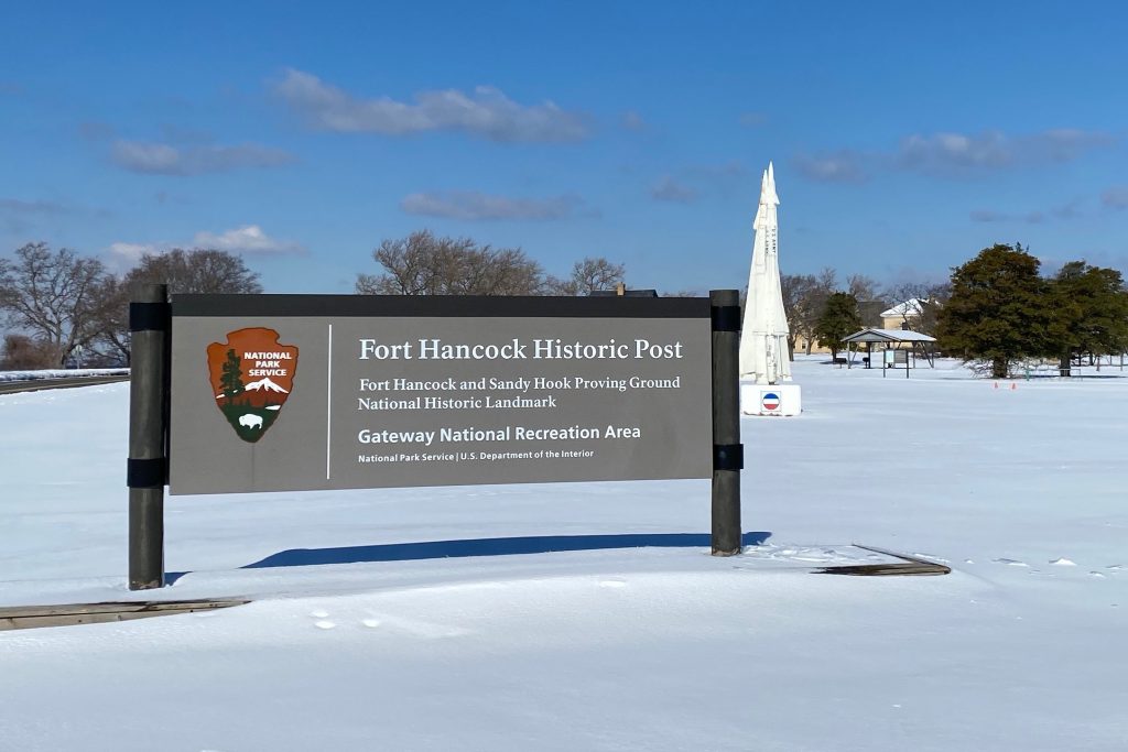 Fort Hancock Historic Post welcome sign with missile behind it at Sandy Hook NJ beach